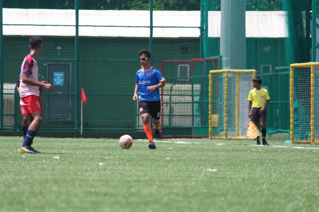 Aarav in a blue and orange kit, number 31, bringing the ball forward on an artificial pitch